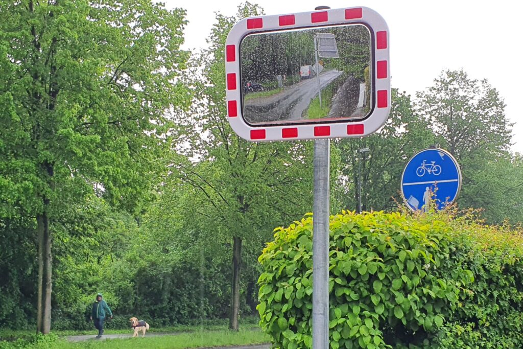 Der Verkehrsspiegel ermöglicht einen Blick in den Radweg in Richtung Norden. Doch auch wegen der großen Bäume, die den Bereich verdunkeln, ist die Sicht nicht besonders gut.