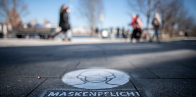 Ein Logo auf dem Boden weist auf die Maskenpflicht am Dortmunder Phoenix-See hin.