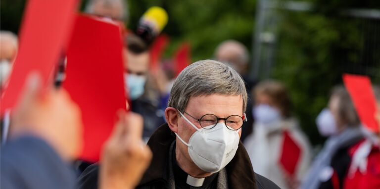 Kardinal Rainer Maria Woelki, Erzbischof von Köln, geht durch einen Spalier aus Gemeindemitgliedern, die ihm vor der Kirche St. Maria vom Frieden die Rote Karte zeigen. Woelki besucht die Gemeinde zu einem Krisengespräch.
