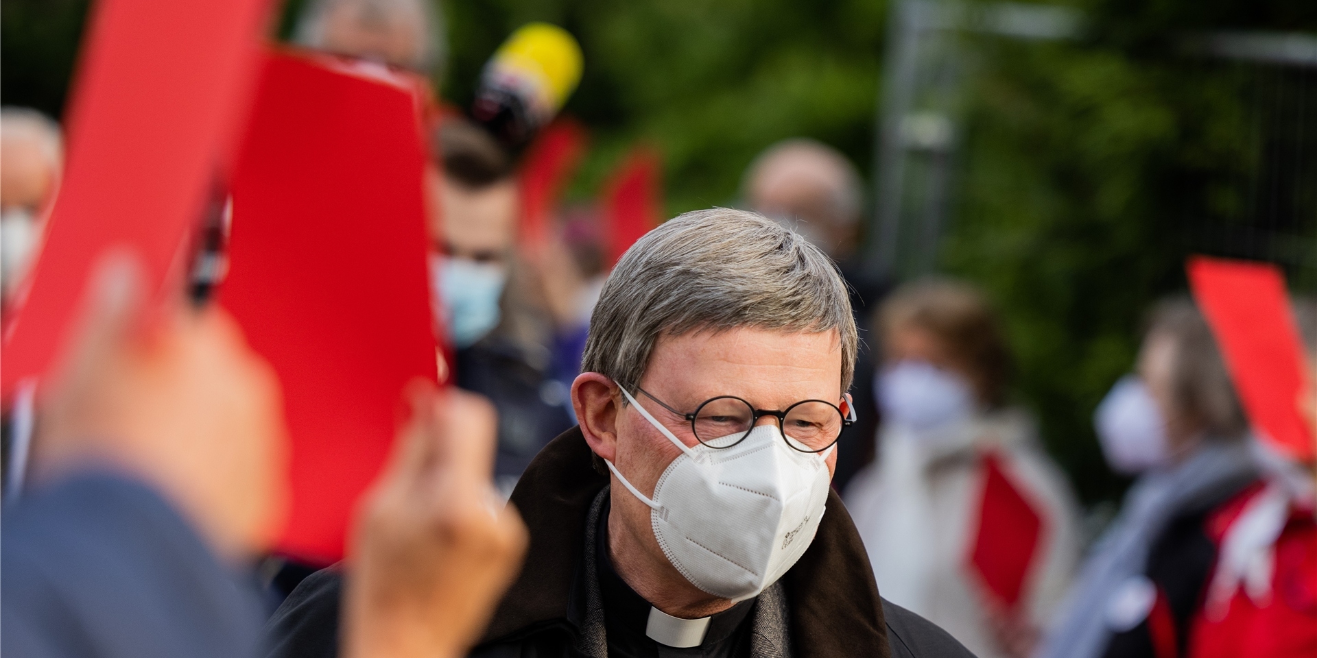 Kardinal Rainer Maria Woelki, Erzbischof von Köln, geht durch einen Spalier aus Gemeindemitgliedern, die ihm vor der Kirche St. Maria vom Frieden die Rote Karte zeigen. Woelki besucht die Gemeinde zu einem Krisengespräch.