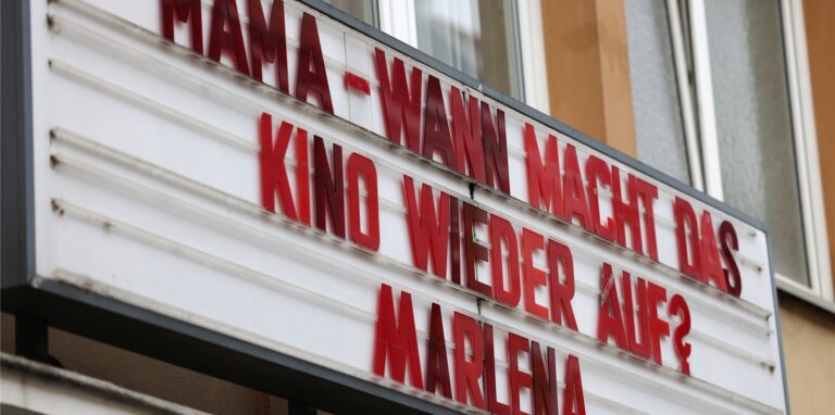 Auf der Anzeigetafel an einem Kino steht der Schriftzug „Mama – wann macht das Kino wieder auf“.