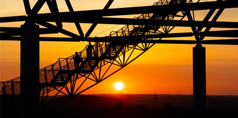 Zwei Menschen laufen bei Sonnenaufgang über eine Treppe des Tetraeders.