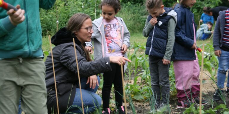Kita-Leiterin Natalie Blendorf erklärt den Kindern, was im Beet zu tun ist,