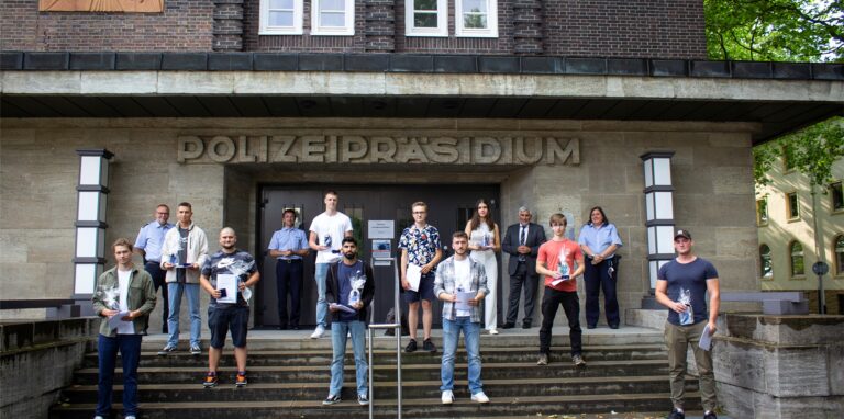 Zehn Helfer stehen mit Beamten vor dem Polizeipräsidium Bochum. Die Augenzeugen hatten Polizisten nach einem Unfall aus deren brennendem Streifenwagen gerettet.