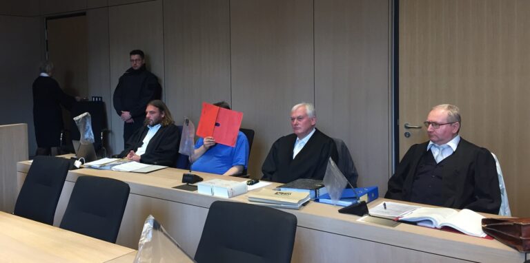 Der Angeklagte sitzt beim Prozessauftakt an der Seite seiner Verteidiger.