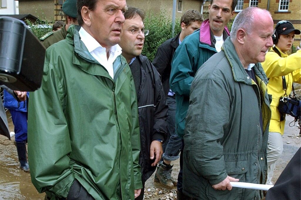 Bundeskanzler Gerhard Schröder (SPD, l) und der sächsische Ministerpräsident Georg Milbradt (CDU) gehen durch die nach dem Hochwasser verwüstete sächsische Kreisstadt Grimma (Archivfoto vom 14.08.2002).