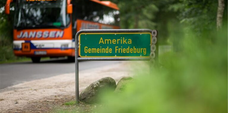 Ein Bus fährt an dem Ortsschild Amerika vorbei, einem Ortsteil von Friedeburg. Foto: Mohssen Assanimoghaddam/dpa