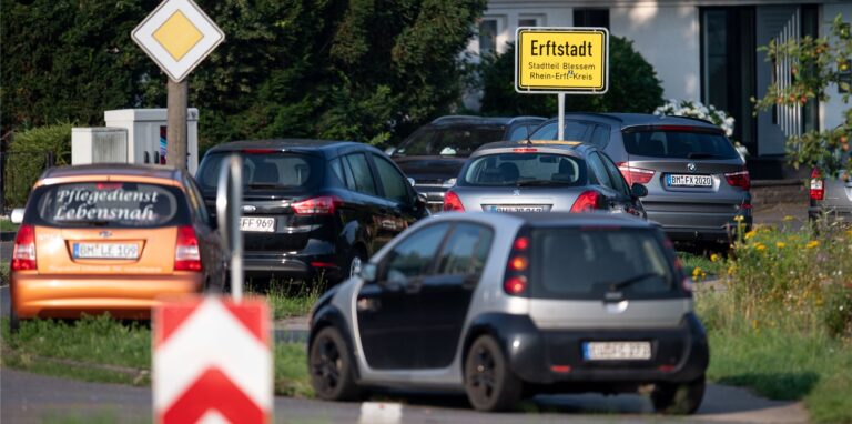 Autos parken am Ortseingang des Stadtteils Blessem. Die Anwohner hoffen, dass sie heute zumindest kurz wieder in ihre Häuser dürfen.