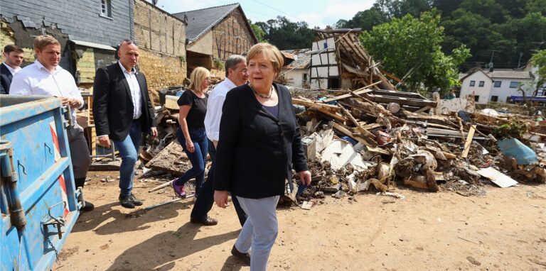Bundeskanzlerin Angela Merkel (CDU, M) und der Ministerpräsident von Nordrhein-Westfalen Armin Laschet (CDU, 3.v.l) besichtigen ein Lager mit Lebensmitteln bei ihrem Besuch im vom Hochwasser betroffenen Gebiet von Bad Münstereifel.