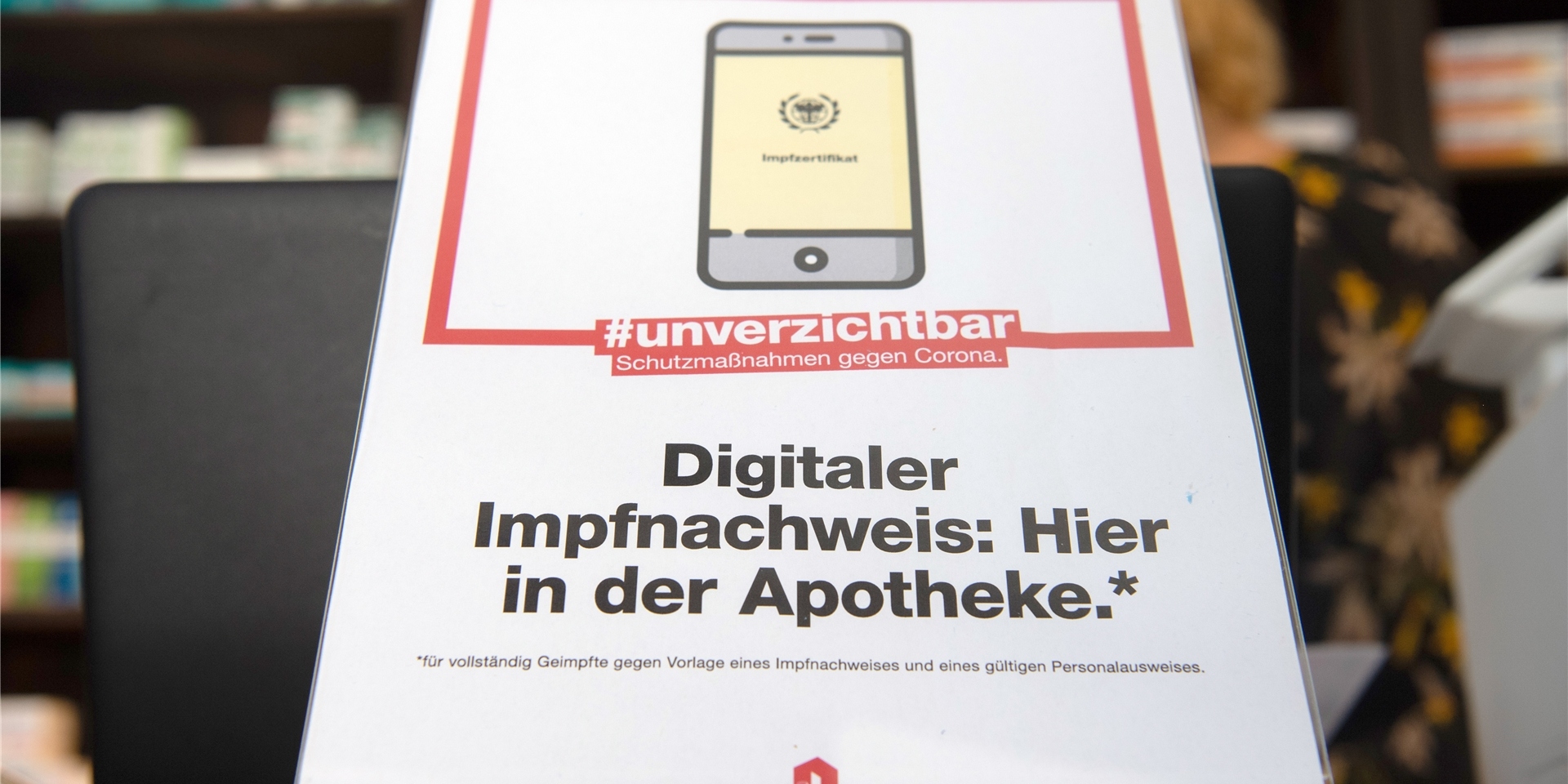 Ein Schild mit dem Aufdruck „Digitaler Impfnachweis: Hier in der Apotheke“ steht in einer Apotheke. Aktuell ist dieser Service nicht mehr möglich.