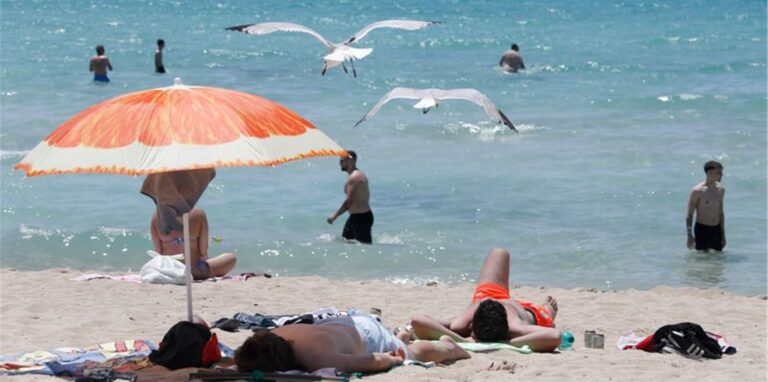 Touristen genießen die Sonne am Strand von Arenal. Foto: Clara Margais/dpa
