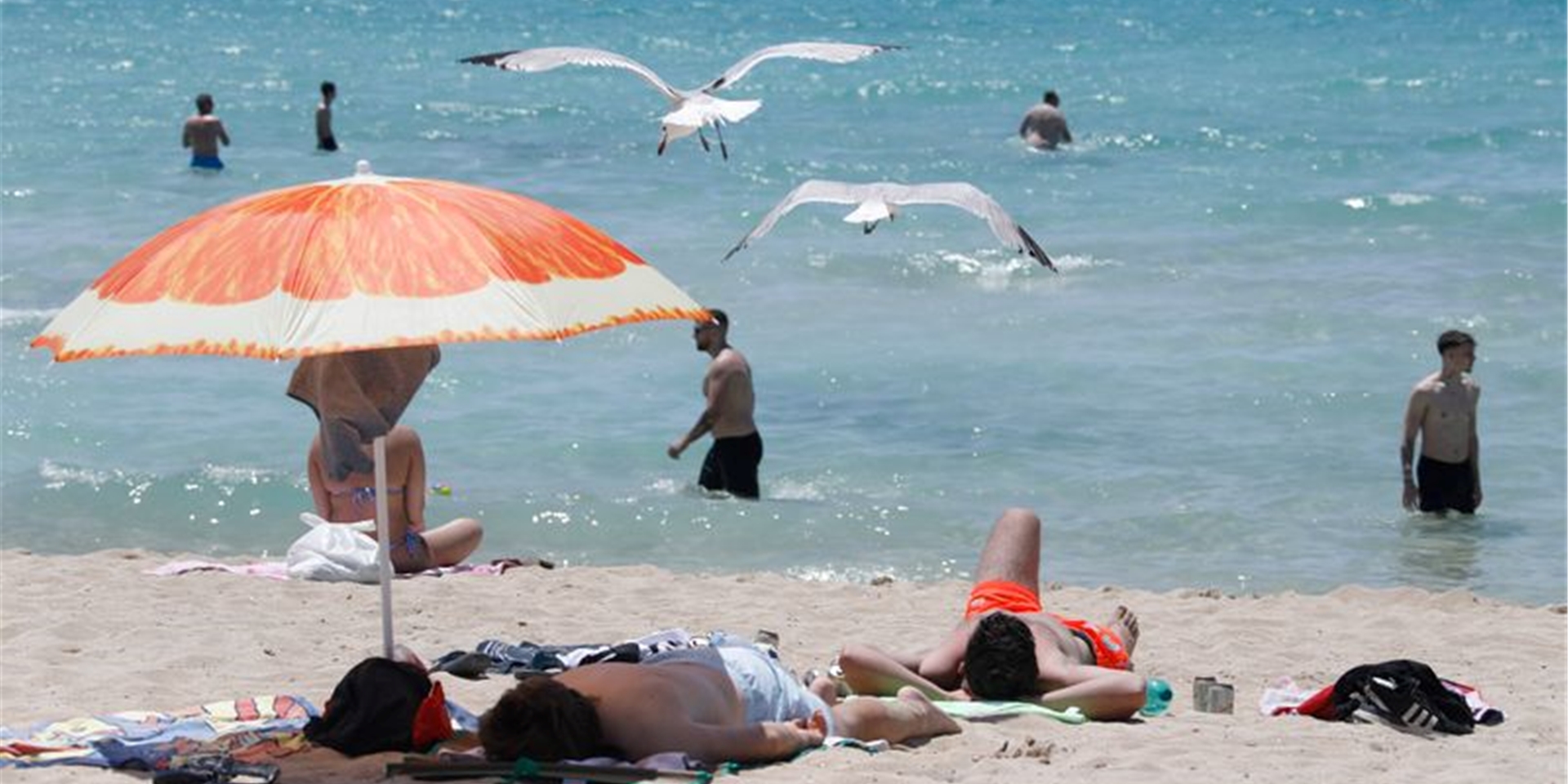 Touristen genießen die Sonne am Strand von Arenal. Foto: Clara Margais/dpa