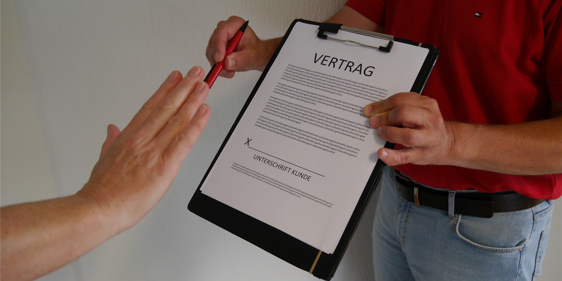 Ein Mann bietet einer anderen Person einen Vertrag zur Unterschrift an.