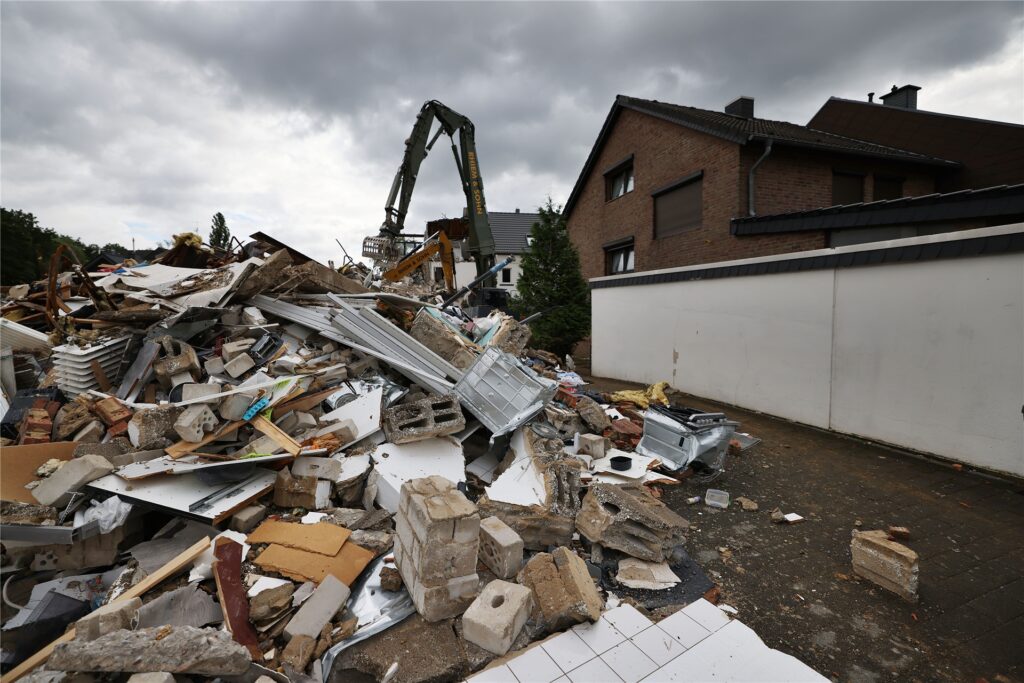 title attribut Hier kommt man nur noch mit dem Bagger durch: Wie auf einem Trümmerfeld sieht es nach dem Hochwasser in Erftstadt-Blessem aus.