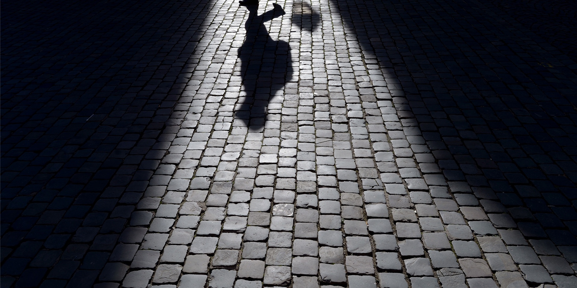 Der Schatten eines Mannes auf einem Kopfsteinpflaster