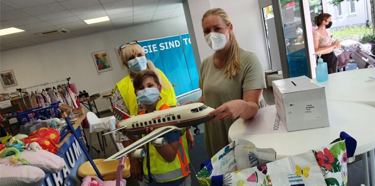 Basar-Organisatorin Christine Kumpf (l.) und ihr Enkel Noah, der als Helfer mitarbeitet, zeigen ein Playmobil-Flugzeug, das Josefine Kniza gerade erstanden hat.
