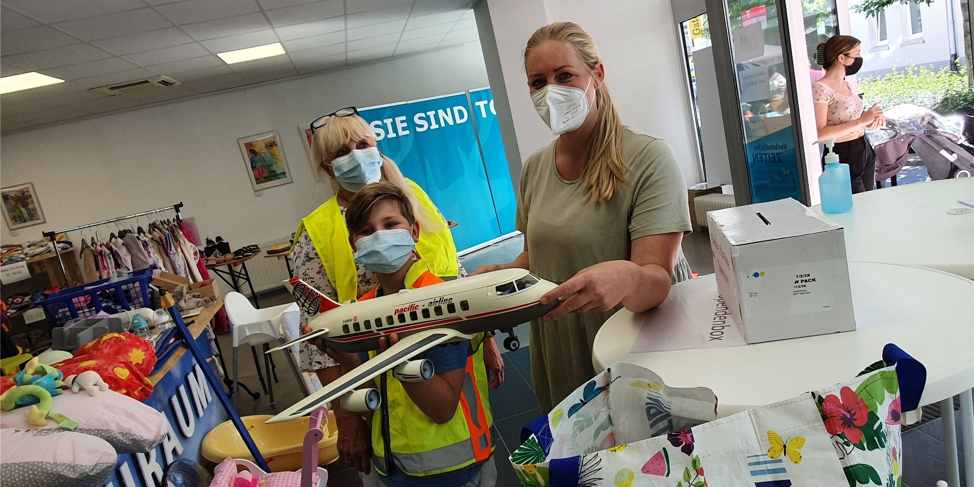 Basar-Organisatorin Christine Kumpf (l.) und ihr Enkel Noah, der als Helfer mitarbeitet, zeigen ein Playmobil-Flugzeug, das Josefine Kniza gerade erstanden hat.