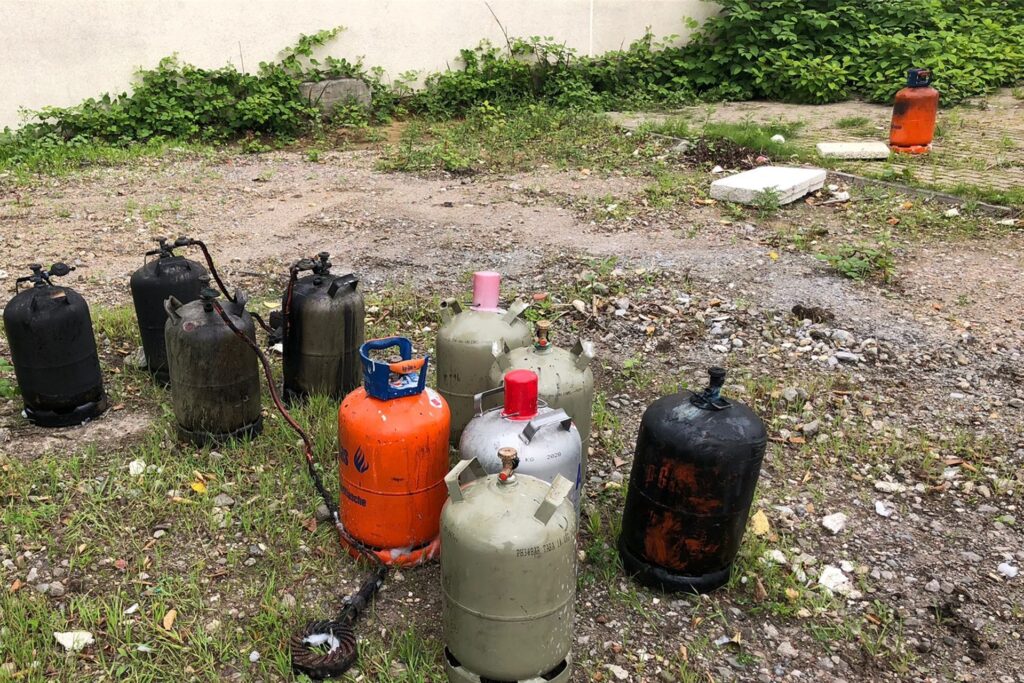 title attribut Neben den Behältern mit Chemikalien holen Feuerwehrleute auch mehrere Gasflaschen aus dem Gebäude.