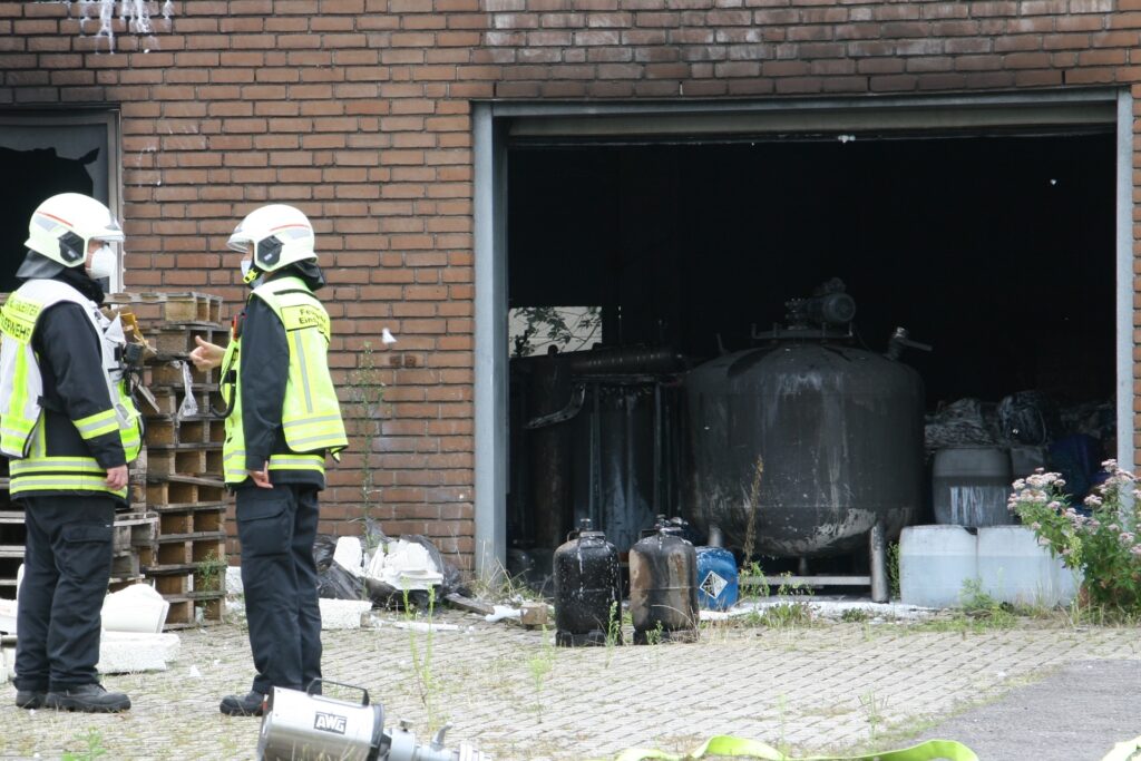Einsatzkräfte der Feuerwehr stehen vor der Garage, in der zahlreiche Gasflaschen und Chemikalienkanister lagern. In dem großen Tank befand sich ein Vorprodukt für die Amphetamin-Herstellung. Einsatzkräfte der Feuerwehr stehen vor der Garage, in der zahlreiche Gasflaschen und Chemikalienkanister lagern. In dem großen Tank befand sich ein Vorprodukt für die Amphetamin-Herstellung.