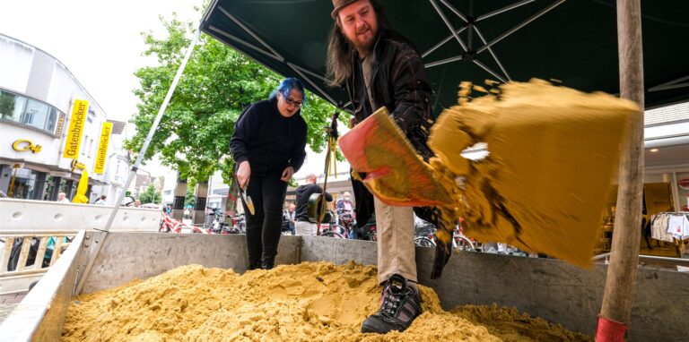 Schwungvoll gräbt der Künstler Paul, das lebende Kunstwerk, den Sand auf dem Anhänger vor dem Glashaus um. Seine Partnerin, die Mysteriöse Miriam, fischt allerlei rostige Geräte heraus und rätselt, was es damit auf sich hat.