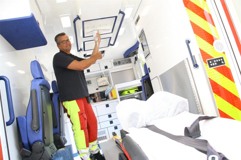 title attribut Notfallsaniäter Carsten Iwanowski zeigt im Rettungswagen die besser platzierten Halterungen für die Infusionen. Bisher waren diese so angeordnet, dass der Schlauch oft nur mit Mühe bis zum Arm des Patienten reichte.