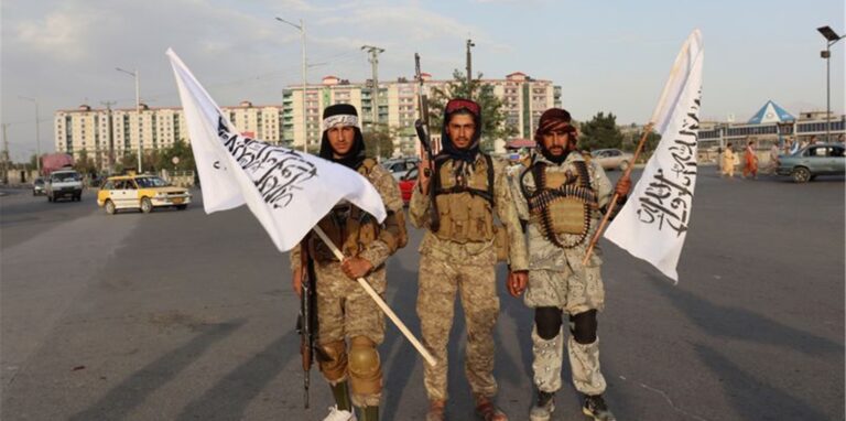 Kämpfer der Taliban stehen mit Flaggen auf einer Straße in der afghanischen Hauptstadt Kabul.
