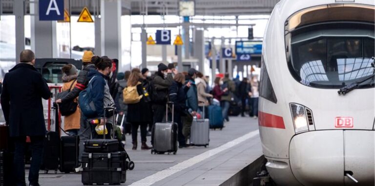 Reisende neben einem ICE am Münchener Hauptbahnhof.