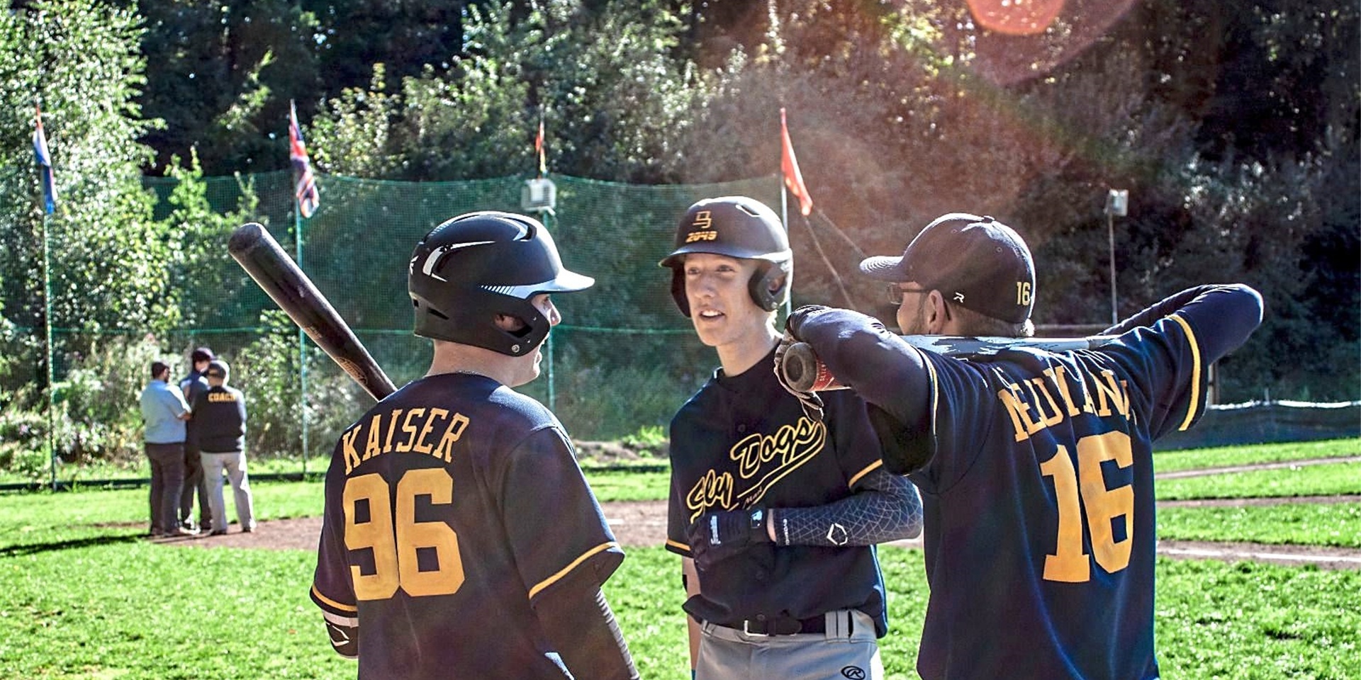 Drei Baseballspieler stehen auf einem Spielfeld.