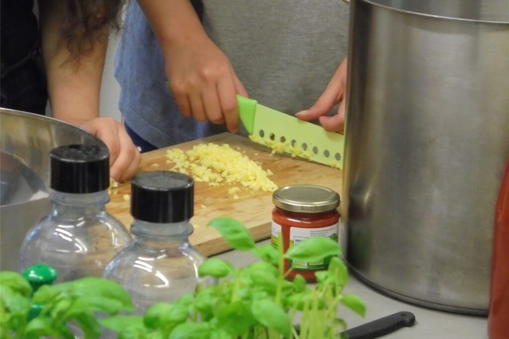 title attribut In der Küche auf dem Hof Wessels werden Knoblauch und Kräuter für das vegane Mittagessen gehackt.