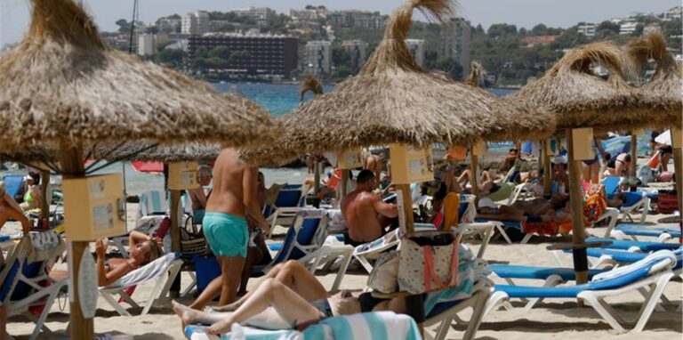 Einheimische und Touristen liegen am Strand Cala Major in Palma de Mallorca.