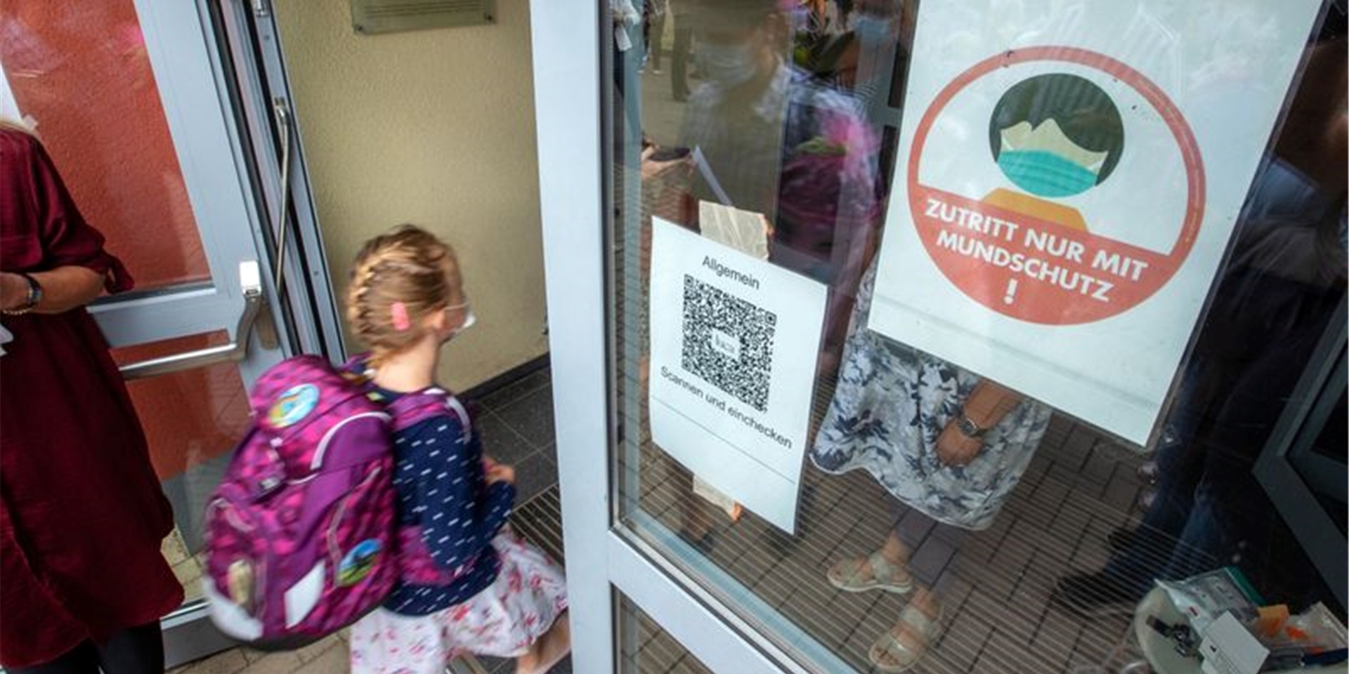 Schulanfänger und ihre Eltern gehen nach Corona-Kontrollen und mit Mund-Nasen-Schutz zur Einschulungsfeier in Schwerin.