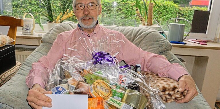 Stolz präsentiert der ehemalige Hausmeister der Gemeinde St. Ludgerus, Bernd Anhut, einen der vielen Präsentkörbe, die er zum Abschied erhalten hat. Besonders freut ihn daran die beiliegende Karte mit den lieben Worten.
