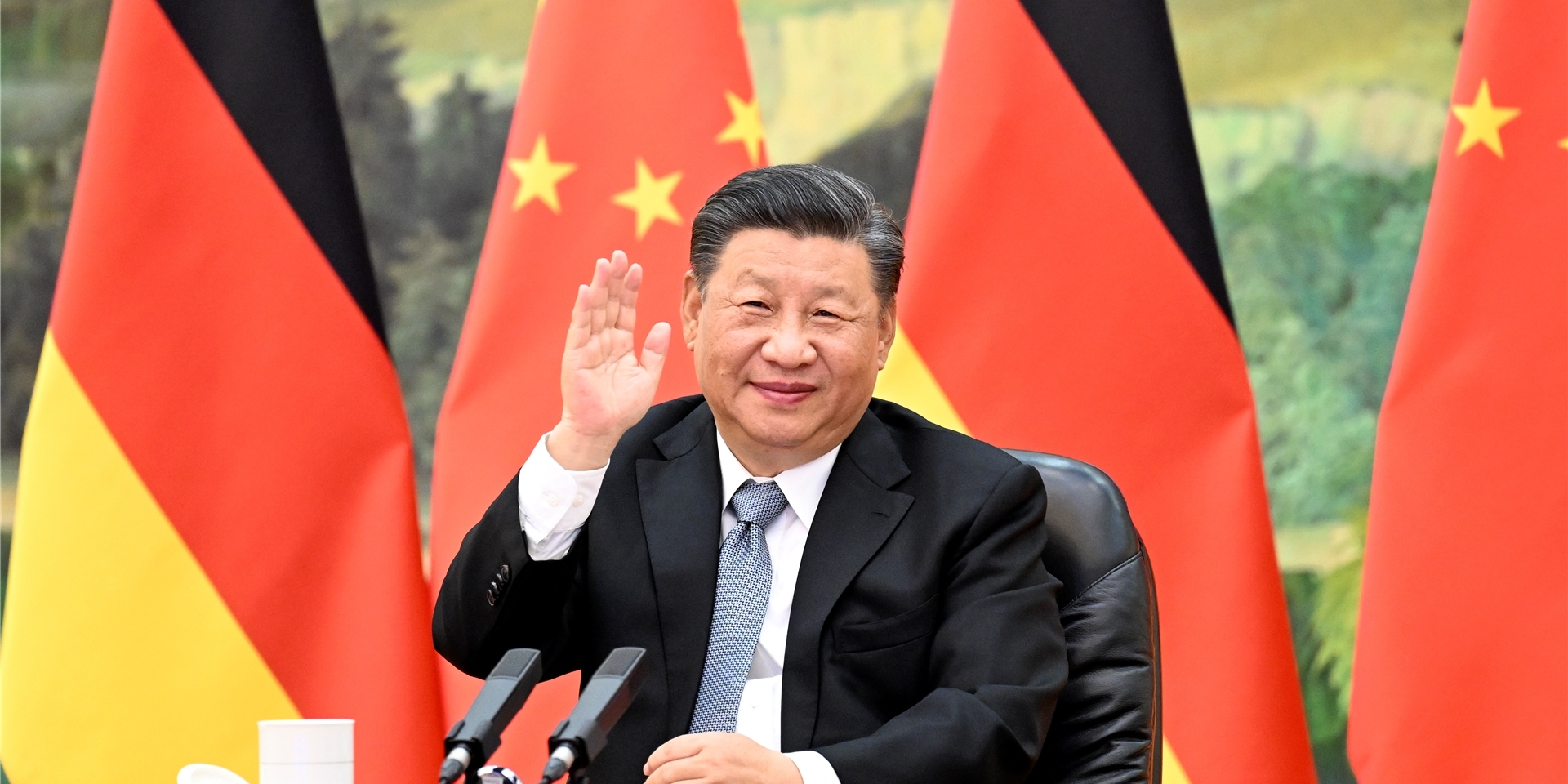 Xi Jinping, Präsident von China, sitzt vor den Flaggen von China und Deutschland.