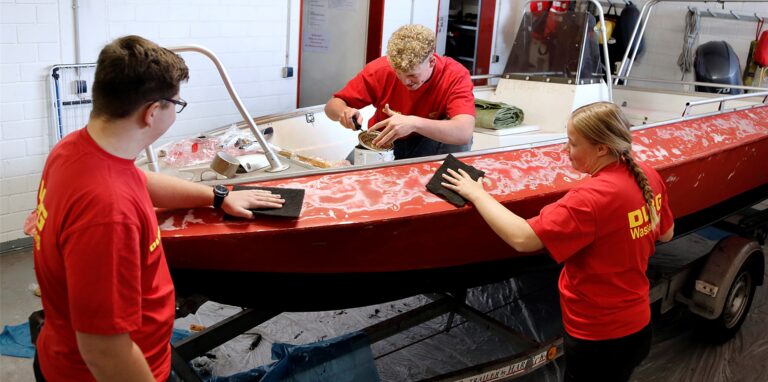Die drei Bufdis Lars Vospohl, Ben Wester und Maike Jahnke, pflegen und reparieren das Rettungsboot Lea.