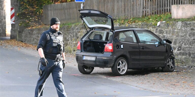 Ein Polizist geht an einem VW Polo vor einer Kindertagesstätte im Ortsteil Gertenbach vorbei. Dort soll ein Autofahrer absichtlich in eine Gruppe Kinder gefahren sein.