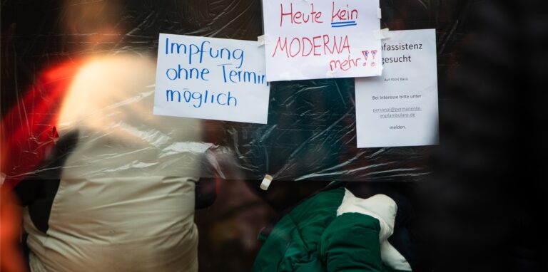 Ein Plakat weist Menschen an einem Impfzentrum auf mögliche Impfungen ohne einen Termin hin.