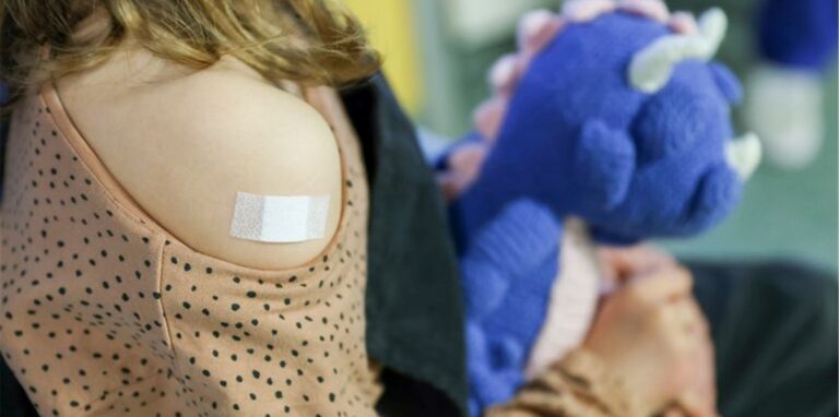 Ein Pflaster klebt auf den Arm eines Mädchens, nachdem es gegen das Covid-19-Virus geimpft wurde