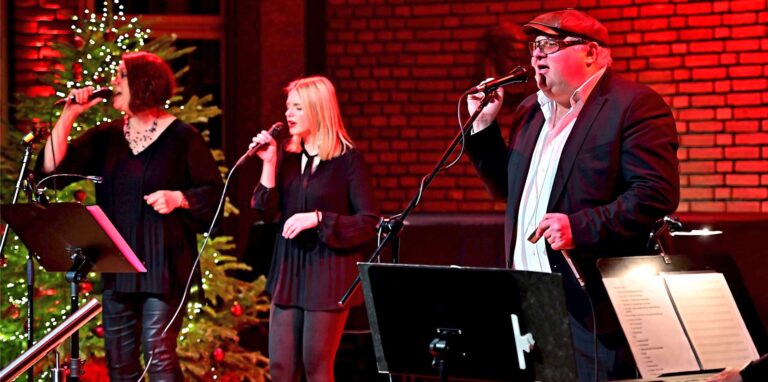 Weiße Weihnacht im rot erleuchteten Saal der Erlöserkirche: Heike Meering, Nina Zaborowski und Chris Kramer (v. l.) versetzten das Publikum in Weihnachtsstimmung.