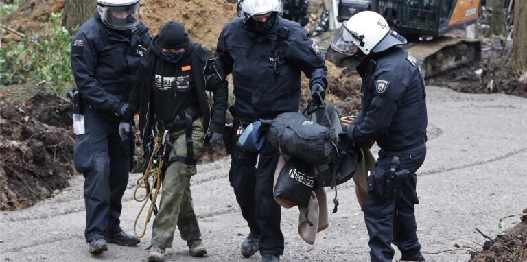 Polizisten beginnen die Räumung eines besetzten Waldstücks in Wuppertal, dabei führen sie eine der Aktivistinnen (2.v.l.) ab.