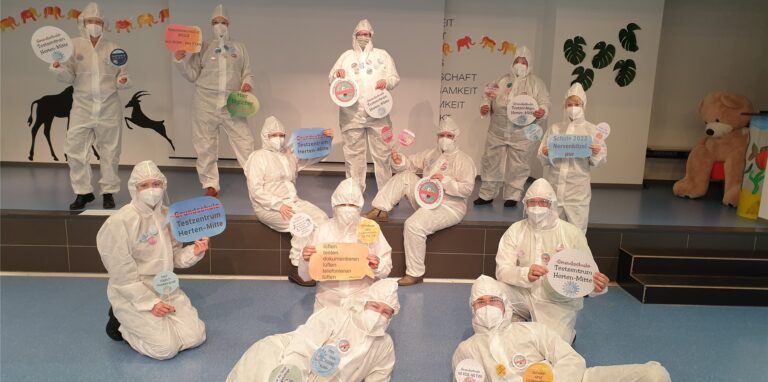 Protestaktion in voller Corona-Schutzausrüstung: Auf humorvolle Art und Weise machen die Lehrer der Grundschule-Herten Mitte auf die missliche Corona-Test-Situation an den Grundschulen aufmerksam.