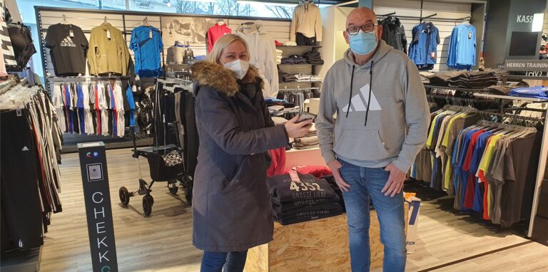 Wie selbstverständlich zeigt Gerda Falk am Eingang vom Intersport-Fachgeschäft von Christoph Ules Impfnachweis und Ausweis. Die neue Regelung ist bei vielen Kunden noch nicht angekommen.