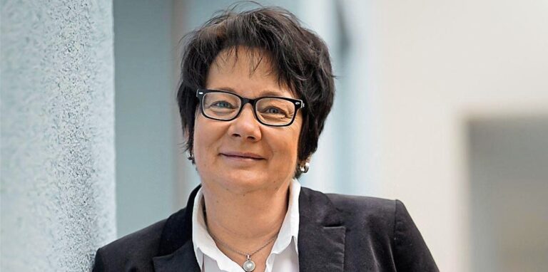 Susanne Schäfer lehnt an einer weißen Wand.