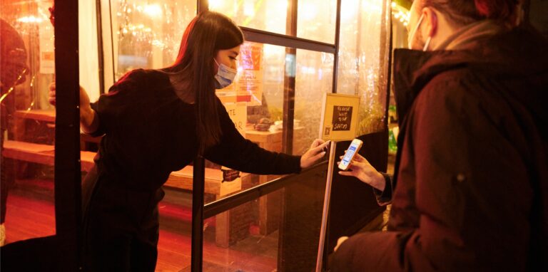 Eine Mitarbeiterin eines Restaurants kontrolliert den Impfstatus zweier Personen. Ins Restaurant in Deutschland darf aktuell nur, wer geimpft und getestet ist.