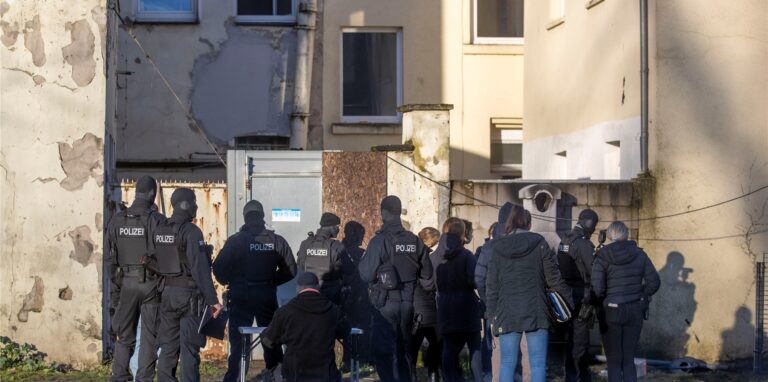 Polizisten stehen vor einem Hinterhof im Stadtteil Laar. Die Polizei hat bei einem Großeinsatz zahlreiche Wohnungen und einen internationalen Kulturverein im Duisburger Norden durchsucht.