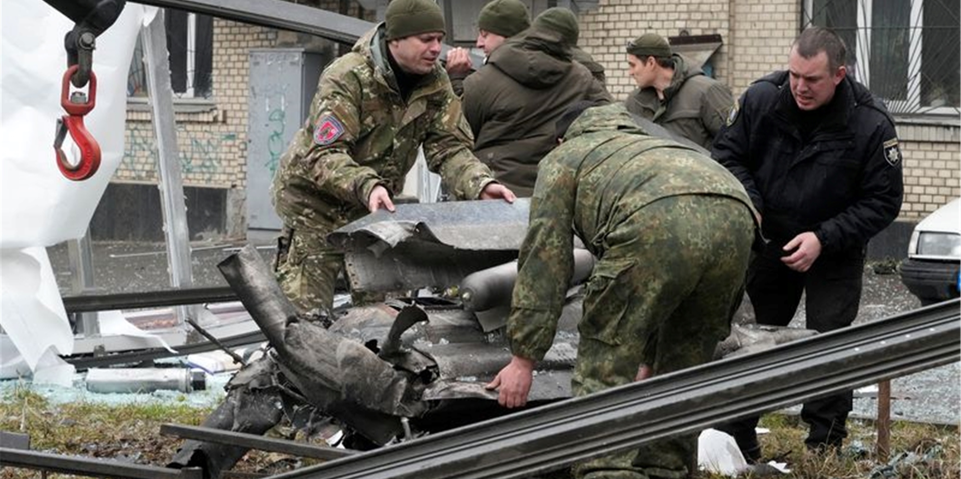 Arbeiter räumen die Trümmer einer Rakete auf einen Lastwagen, nach einem russischen Beschuss.