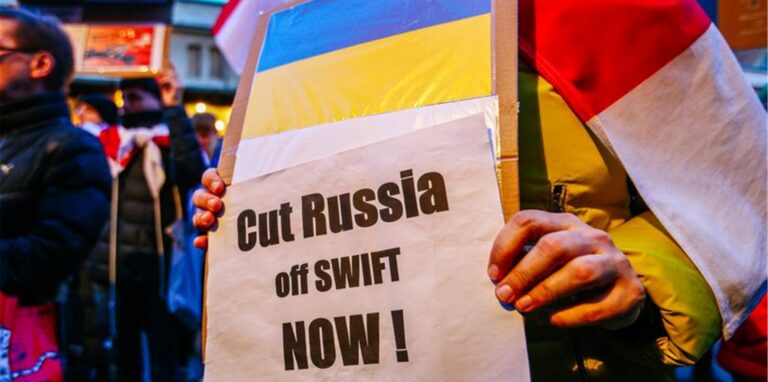 Ein Demonstrant hält ein Schild mit der ukrainischen Flagge und der Aufschrift „Russland jetzt abschneiden!“.