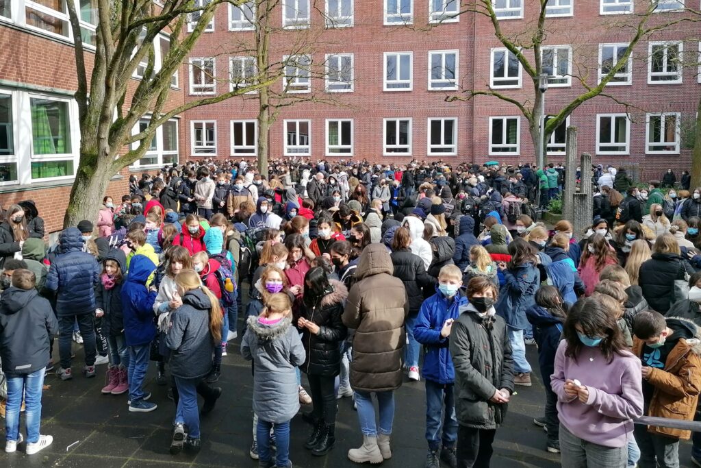Hunderte Schüler/innen und Lehrer/innen kommen zur spontanen Friedensaktion des Städtischen Gymnasiums Herten zusammen. Hunderte Schüler/innen und Lehrer/innen kommen zur spontanen Friedensaktion des Städtischen Gymnasiums Herten zusammen.