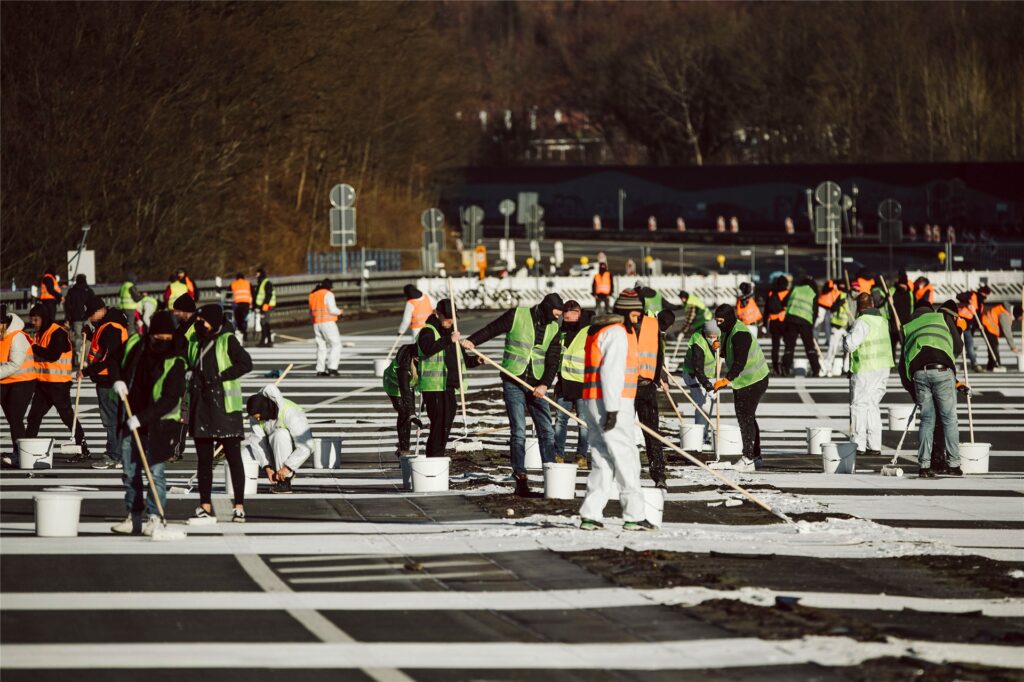 Zahlreiche Künstler stehen auf der gesperrten Rahmedetalbrücke der Autobahn 45 und malen eine Friedensbotschaft auf den Asphalt.