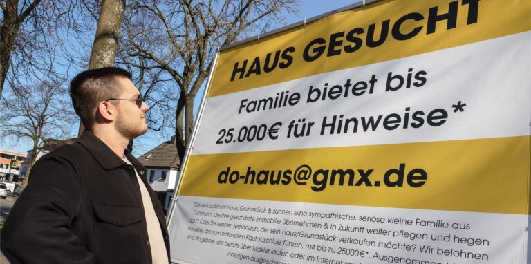 Mit Verwunderung reagieren Passanten auf die ungewöhnliche Immobilien-Anzeige am Straßenrand.