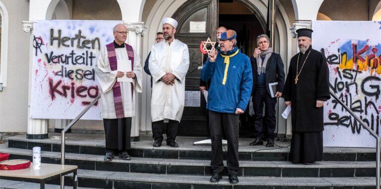 Organisator Andreas Dickel eröffnet im Kreise der Geistlichen vor der Kirche Heiliger Dimitrios das Friedensgebet.